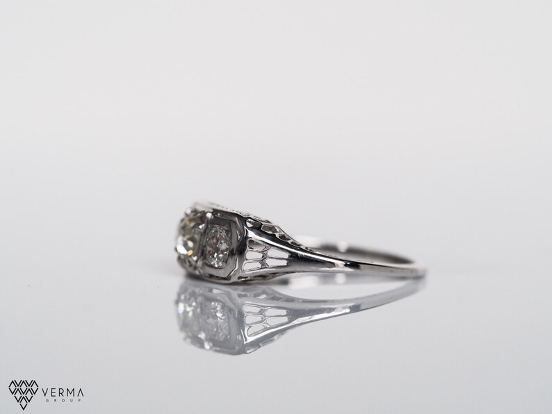 May include: A silver engagement ring with a single, round, clear diamond set in a filigree design.