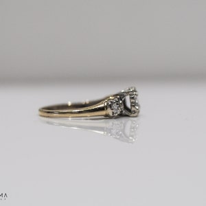 May include: A gold and silver engagement ring with a large center diamond and smaller diamonds on the band.