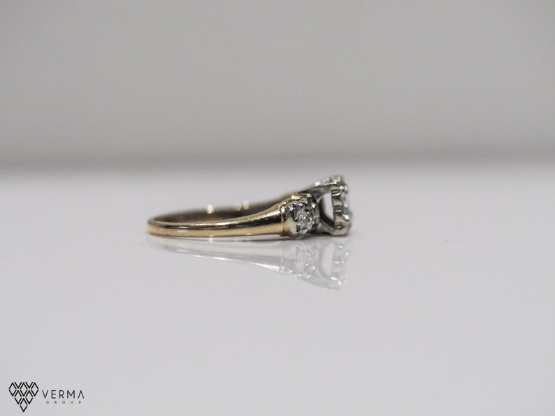 May include: A gold and silver engagement ring with a large center diamond and smaller diamonds on the band.