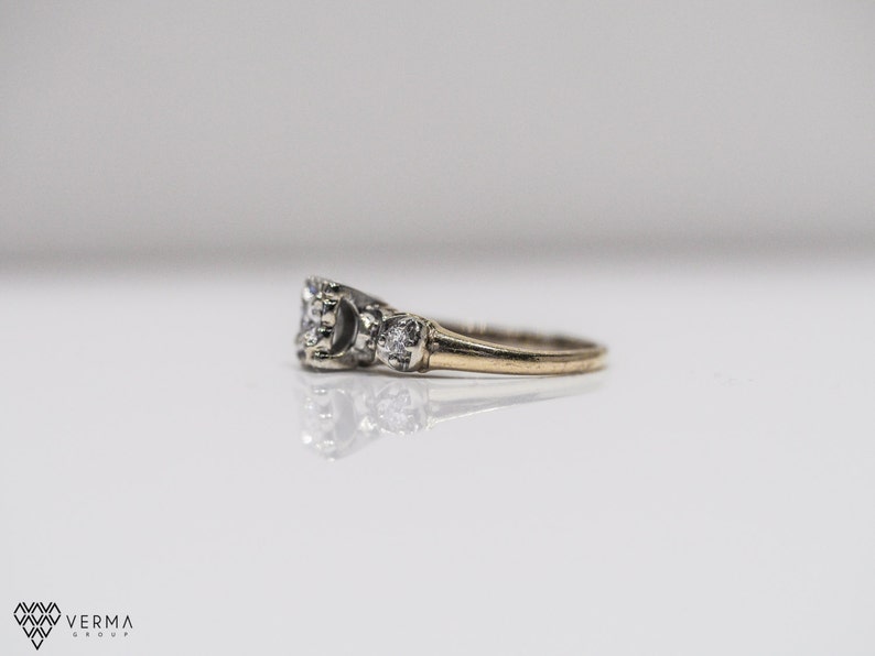 May include: A gold band ring with three round diamonds. The center diamond is larger than the two side diamonds.