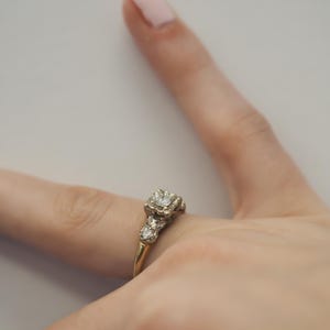 May include: A gold ring with a large, clear diamond in the center and smaller diamonds on the band.