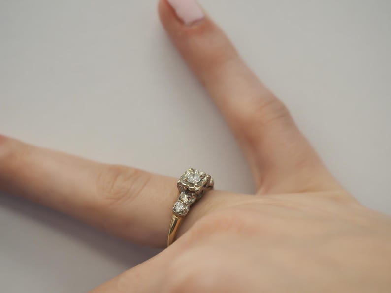 May include: A gold ring with a large, clear diamond in the center and smaller diamonds on the band.
