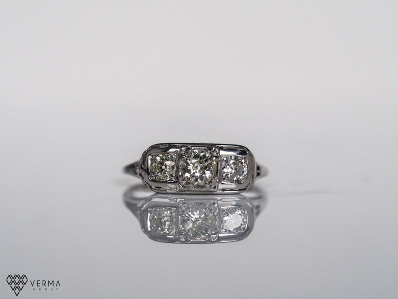 May include: A silver ring with three round diamonds set in a rectangular band.