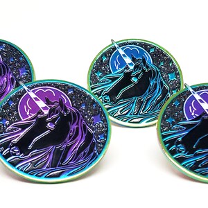 May include: Four iridescent enamel pins featuring a black unicorn with a white horn against a dark blue background with a purple moon and white stars.