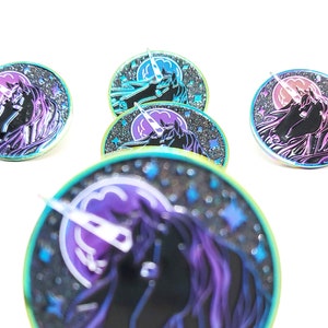 May include: Five iridescent enamel pins featuring a black unicorn with a rainbow horn and a crescent moon in the background. The pins have a sparkly, glittery finish and are set against a white background.