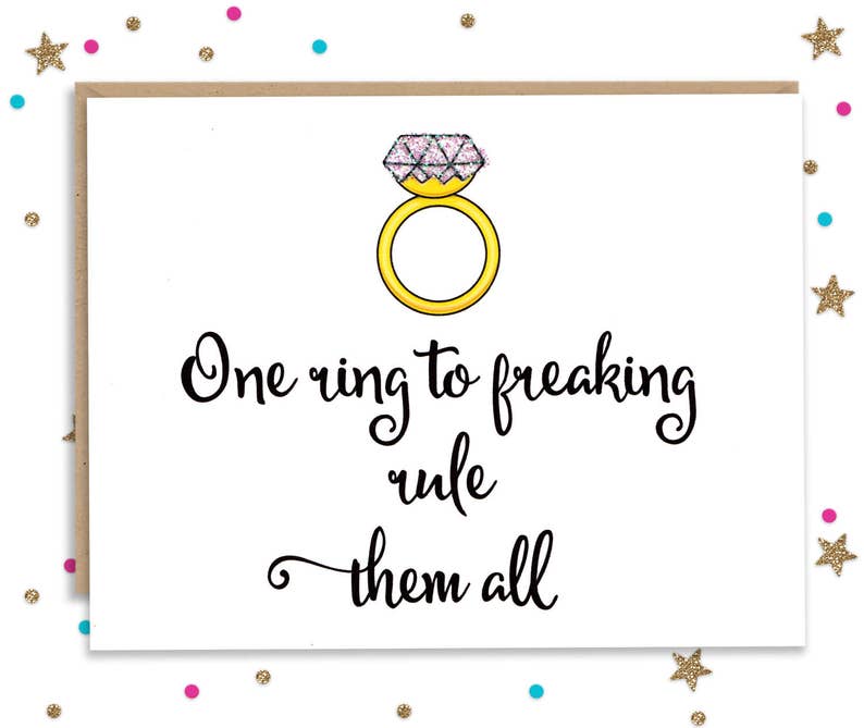 May include: A white card with a gold ring with a pink diamond on top. The card says "One ring to freaking rule them all".