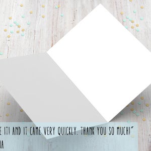 May include: A white card with a blank inside and a folded edge. The card is on a wooden surface with blue and yellow confetti. The text on the card reads "I LOVE IT! AND IT CAME VERY QUICKLY. THANK YOU SO MUCHI" - OLIVIA