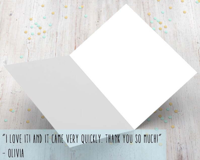 May include: A white card with a blank inside and a folded edge. The card is on a wooden surface with blue and yellow confetti. The text on the card reads "I LOVE IT! AND IT CAME VERY QUICKLY. THANK YOU SO MUCHI" - OLIVIA
