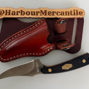 May include: A fixed-blade Old Timer knife with a curved silver blade and a black handle featuring brass rivets and an Old Timer logo. The knife is paired with a dark brown leather sheath that has a belt loop and the text @HarbourMercantile.