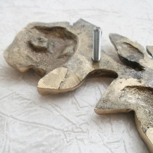 The decoration cames with removable pins for fixing. Also this one may be glued with an adhesive. An adhesive doesn't supplied with the decoration, because it kind depends of a surfase the piece should to fix on.