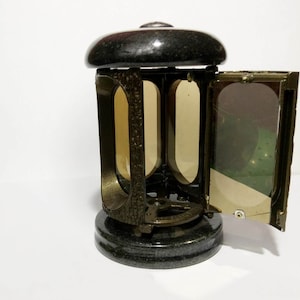 May include: A black granite urn with a bronze-colored metal frame and glass panels. The urn has a hinged door on one side.