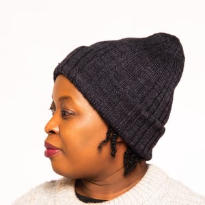 May include: A person wearing a black knit beanie and a light gray sweater.