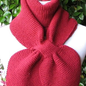 May include: A red knitted scarf with a unique looped design. The scarf is made of a soft, warm yarn and is perfect for keeping you cozy in the winter.