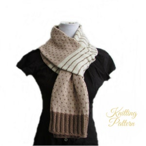 May include: A knitted scarf with a brown and white striped pattern and a brown dotted pattern. The scarf is folded and draped around a mannequin wearing a black shirt.