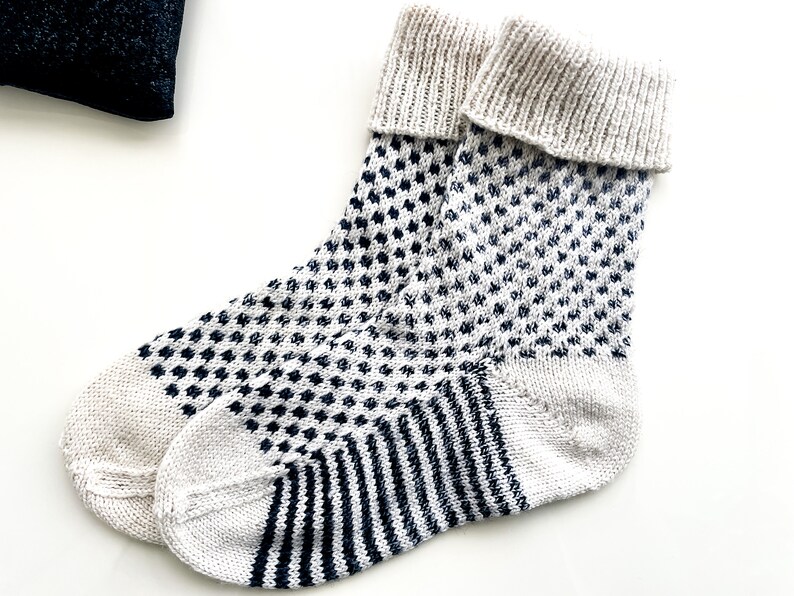 Puede incluir: Un par de calcetines de punto blanco con un patr&oacute;n geom&eacute;trico blanco y negro. Los calcetines tienen un pu&ntilde;o acanalado y un patr&oacute;n de rayas contrastantes en el pie.