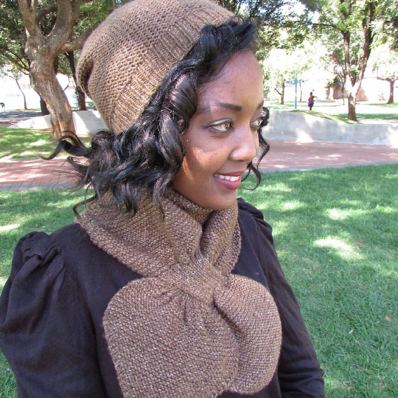 May include: A brown knitted hat and matching scarf. The hat is pulled down over the person's forehead and the scarf is tied in a loose knot around the neck.