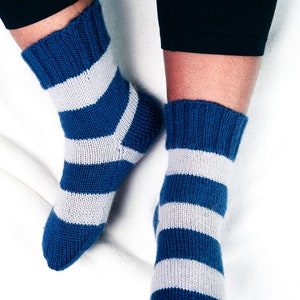 Puede incluir: Un par de calcetines de punto a rayas azules y blancas. Los calcetines están hechos de un material suave y cómodo y tienen un patrón a rayas clásico.