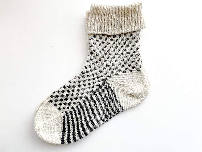 Puede incluir: Calcetines de punto blanco con un patr&oacute;n geom&eacute;trico blanco y negro. Los calcetines tienen un pu&ntilde;o doblado.