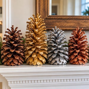 May include: A set of four decorative pinecone sculptures arranged in a row. The pinecones are finished in metallic colors, specifically dark bronze, bright gold, silver, and copper, each featuring detailed, layered scales and a pointed top.