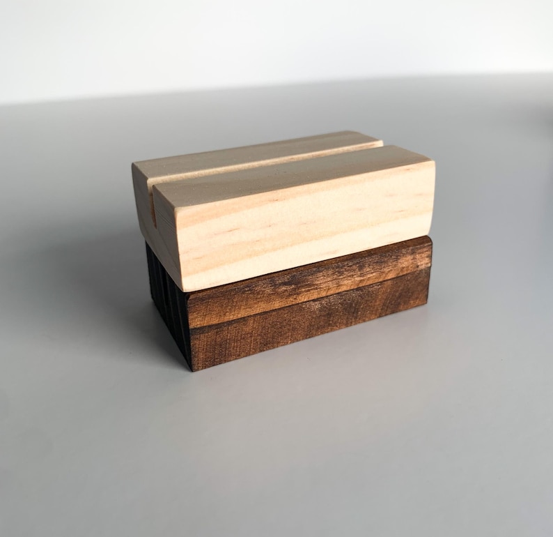 May include: A wooden sign holder with a natural wood finish on top and a dark stained wood base.