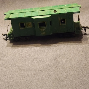 Può includere: Un modello di vagone ferroviario verde con la scritta "W.P. 645" sul lato. Il vagone ha un tetto verde e piccole finestre. Il modello è una replica in miniatura di un vero vagone.
