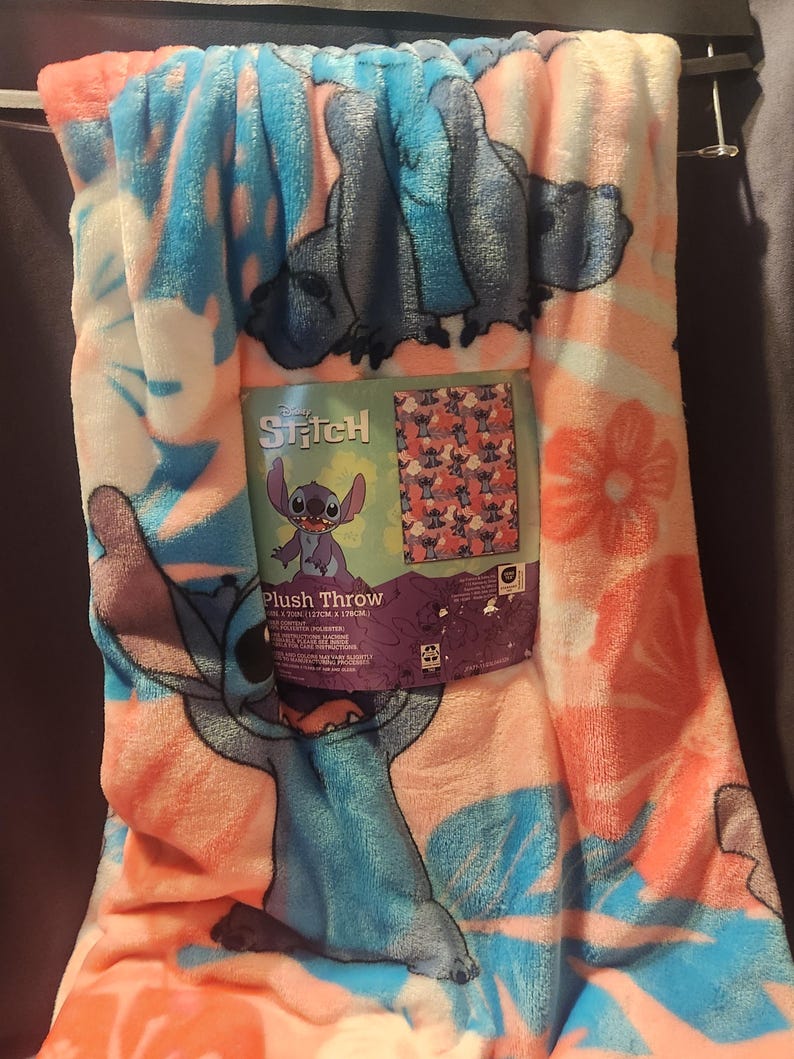 Puede incluir: Una manta de felpa con el personaje Stitch de Lilo & Stitch de Disney. La manta tiene un dise&ntilde;o floral rosa, azul y blanco con ilustraciones de Stitch. El embalaje dice "Stitch Plush Throw". La manta mide 127cm x 178cm.