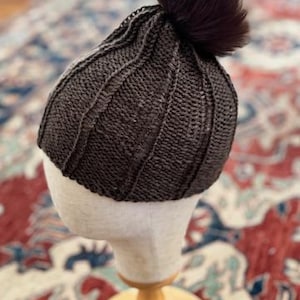 Patrón de gorro Idris: Gorro redondo tejido de abajo hacia arriba con pompón de pelo.