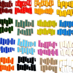 May include: A collection of rectangular ceramic tiles arranged in twenty distinct color groups. Each group contains multiple small, glossy, brick-shaped pieces in shades including red, orange, yellow, green, blue, purple, black, white, and beige.