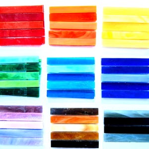 May include: A collection of rectangular glass tiles arranged in nine distinct color groups. The tiles feature various shades of red, orange, yellow, green, blue, purple, brown, black, and white, with some showing marbled or translucent textures.