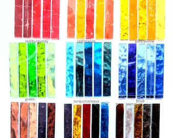 May include: A collection of rectangular glass strips arranged in rows and columns, categorized by color labels including red/burgundy, red/orange, gold/yellow, green, turquoise/aqua, blue, pink/purple, rainbow, and metallic, featuring varied textures.