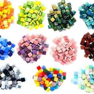 Peut inclure: Douze tas distincts de petites tuiles de mosaïque en verre carrées disposées en grille. Les tas présentent diverses couleurs unies et irisées, notamment orange, jaune, vert citron, vert foncé, sarcelle, bleu, violet, rose, marron, gris et pastel.