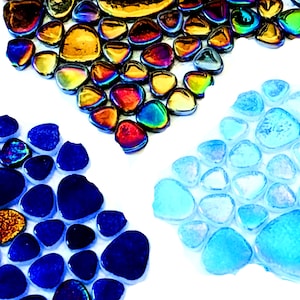 May include: Three groups of iridescent glass pebbles in blue, gold, and light blue. The pebbles are arranged in a pattern on a white background.