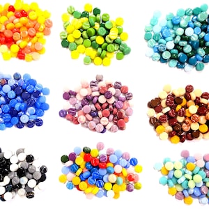 May include: A collection of small, round glass mosaic tiles arranged in nine distinct colour-coded piles. The assortment includes vibrant shades of yellow, orange, red, green, blue, purple, brown, black, white, and multi-coloured pastel blends.
