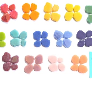May include: A collection of small, smooth, pebble-shaped glass tiles arranged in groups of four. The tiles come in a variety of colors including red, orange, yellow, green, blue, purple, pink, and white, with the white tiles on a blue square.