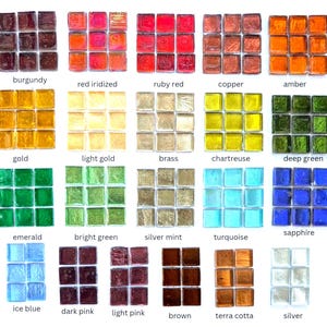 May include: A collection of square glass mosaic tiles arranged in grids, labeled with color names including burgundy, red iridized, ruby red, copper, amber, gold, light gold, brass, chartreuse, deep green, emerald, bright green, silver mint, turquoise, sapphire, ice blue, dark pink, light pink, brown, terra cotta, and silver.