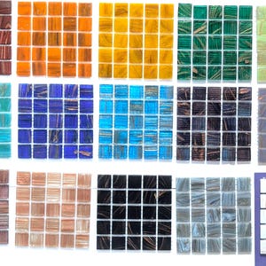 May include: A collection of square glass mosaic tiles arranged in fifteen distinct color groups. Each group features a grid of small, square tiles with subtle marbled or swirled patterns in shades of red, orange, yellow, green, blue, black, and white.