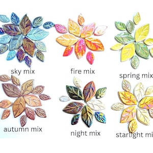 Puede incluir: Seis grupos de azulejos de mosaico con forma de hoja organizados por conjuntos de colores etiquetados como sky mix, fire mix, spring mix, autumn mix, night mix y starlight mix. Cada grupo presenta hojas texturizadas de varios tamaños en tonos azul iridiscente, naranja cálido, amarillo brillante, cobre metálico, carbón oscuro y oro brillante.