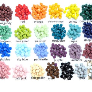 May include: A collection of small, round, flat glass tiles arranged in twenty-eight distinct color groups. Each group is labeled with its color name, including burgundy, red, orange, yellow-orange, yellow, deep green, medium green, lime green, pale green, turquoise, aqua, deep blue, bright blue, sky blue, periwinkle, purple, lavender, deep pink, pink, pale pink, pale peach, brown, black, gray, and white.