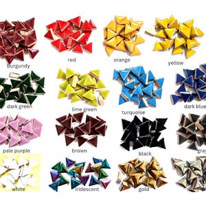 May include: A collection of small triangular ceramic tiles arranged in fifteen color-coded groups. The colors include burgundy, red, orange, yellow, dark green, lime green, turquoise, dark blue, pale purple, brown, black, gray, white, iridescent, gold, and silver.