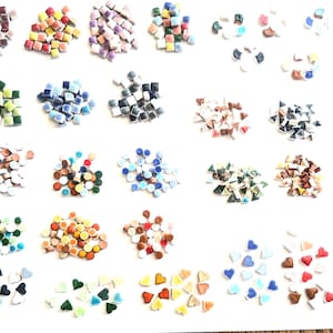 May include: A collection of colorful mosaic tiles and heart-shaped pieces in various colors, including red, blue, green, and yellow. The tiles are square, triangular, and round, perfect for craft projects. The image is shot from above, showing the variety of shapes and colors.