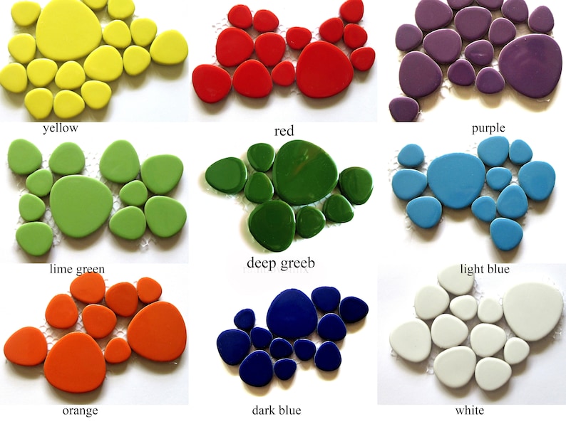 May include: A collection of nine sets of smooth, pebble-shaped glass mosaic tiles in yellow, red, purple, lime green, deep green, light blue, orange, dark blue, and white. Each set is arranged in a cluster on a mesh backing, displaying a glossy finish.