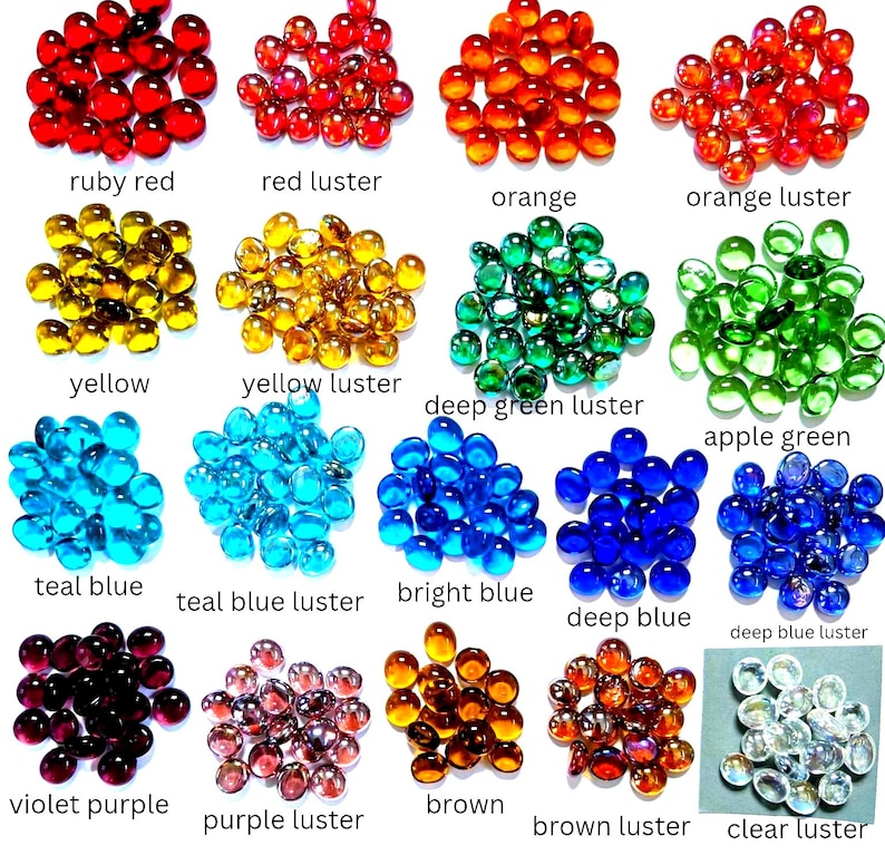 Puede incluir: Una colecci&oacute;n de peque&ntilde;as gemas de vidrio redondas con fondo plano dispuestas en veinte grupos de colores distintos, incluyendo rojo rub&iacute;, rojo lustre, naranja, naranja lustre, amarillo, amarillo lustre, verde profundo lustre, verde manzana, azul cerceta, azul cerceta lustre, azul brillante, azul profundo, azul profundo lustre, violeta, violeta lustre, marr&oacute;n, marr&oacute;n lustre y transparente lustre, cada uno etiquetado con su nombre.