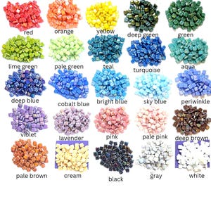May include: A collection of small square glass mosaic tiles arranged in twenty-five distinct color piles. Each pile is labeled with its corresponding color name, including red, orange, yellow, deep green, green, lime green, pale green, teal, turquoise, aqua, deep blue, cobalt blue, bright blue, sky blue, periwinkle, violet, lavender, pink, pale pink, deep brown, pale brown, cream, black, gray, and white.