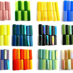 May include: Assortment of 12 glass tiles in various colors, including pink, green, yellow, blue, teal, black, orange, and beige. Each tile is rectangular and has a smooth, glossy finish.