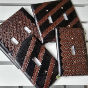 May include: Four decorative light switch covers with different patterns. The patterns include a woven design, a geometric pattern, and a striped pattern. The switch covers are made of a dark brown material with a black background.