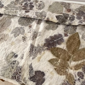 以下が含まれることがあります： 茶色と紫色の葉の模様がついた白い布。布は自然で有機的な見た目と感触です。