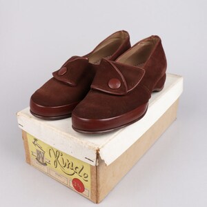 May include: A pair of brown suede shoes with a button detail on the top. The shoes are in a box with a yellow label that says "BV Kindle" and "3 1/2".
