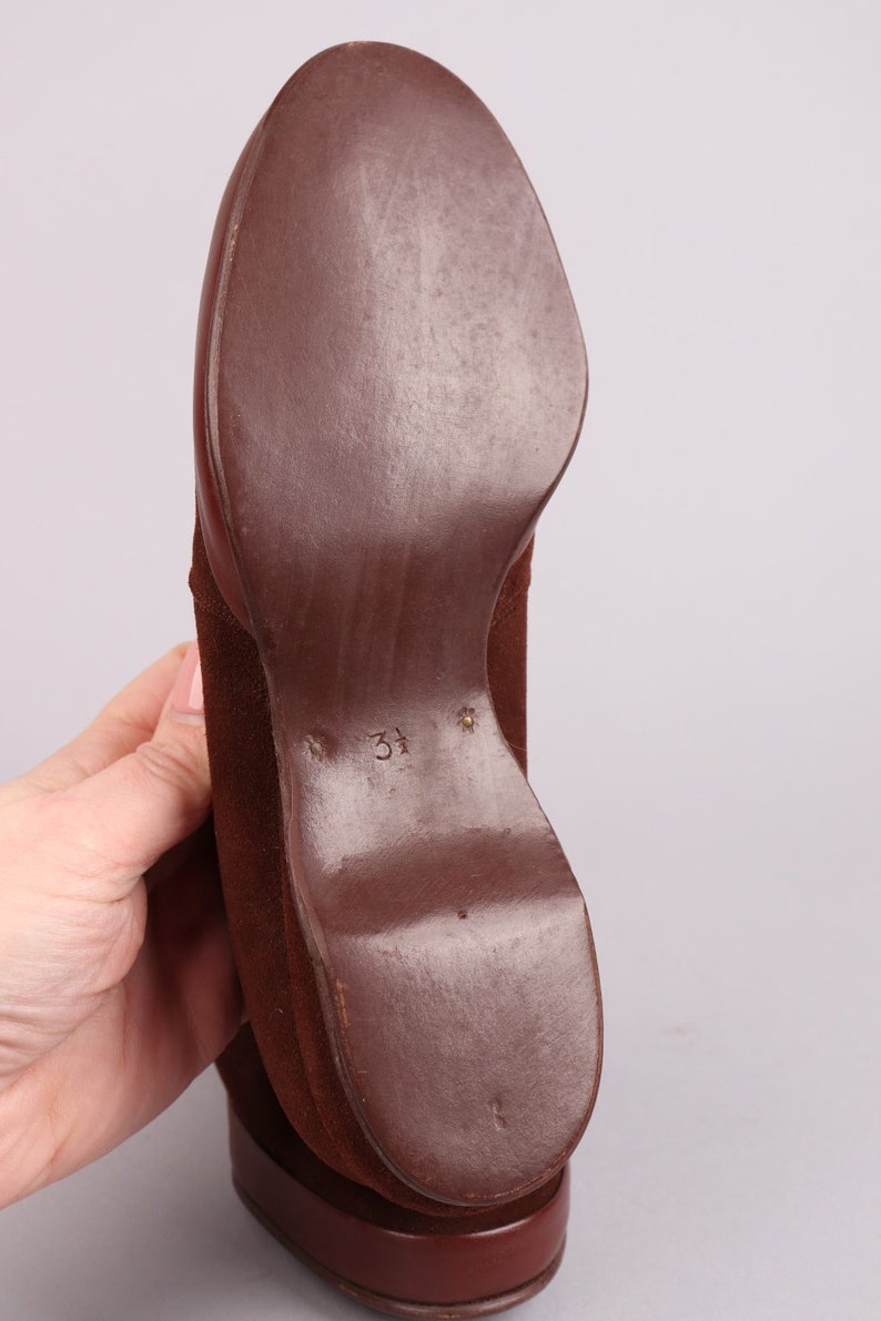 May include: Brown suede shoe with a leather sole. The sole is marked with the number "37".
