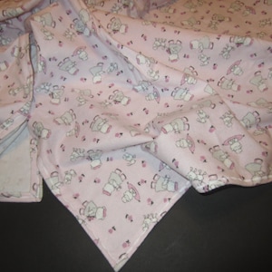 May include: A pink baby blanket with a white and gray print of elephants wearing hats and holding umbrellas.