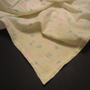 May include: A yellow baby blanket with a light blue and pink pattern of toys and flowers.